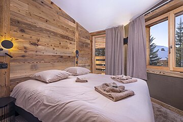A bedroom with a wooden wall and a bed