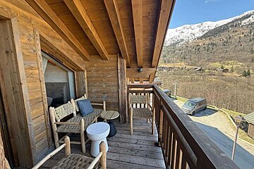 A balcony with chairs and a table with a view of the mountains