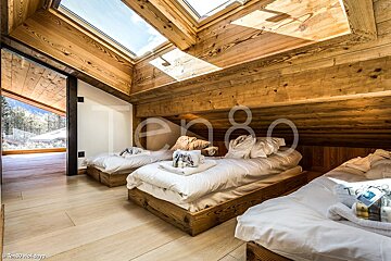A bedroom with three beds and a skylight that says ten80 holidays