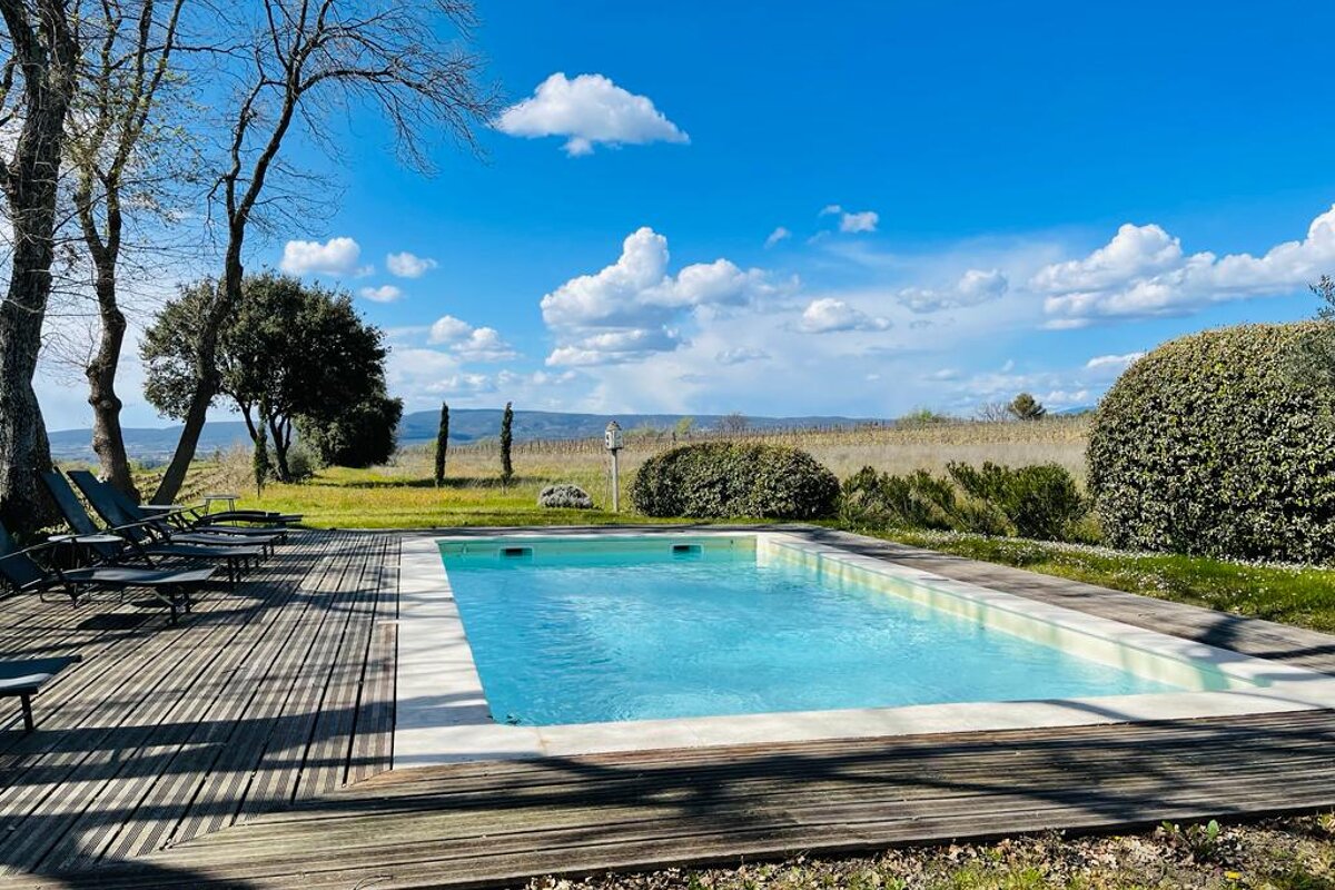 A large swimming pool is surrounded by chairs and trees