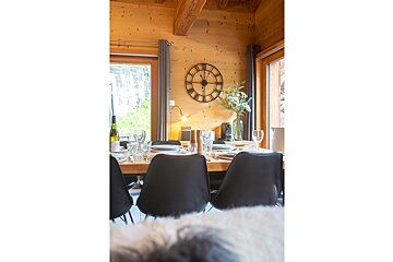 A large clock hangs above a wooden dining table