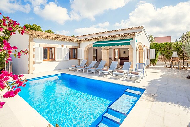 A white house with a large swimming pool in front of it