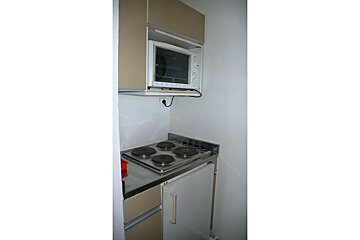A small kitchen with a stove top oven and a microwave
