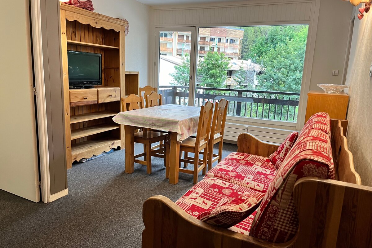 A living room with a table and chairs and a flat screen tv