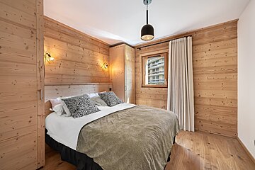 A bedroom with wood paneling and a large bed