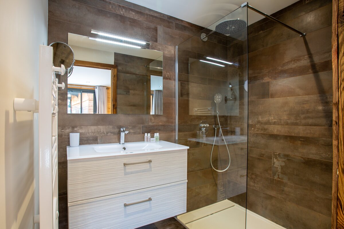 A bathroom with a walk in shower and a sink
