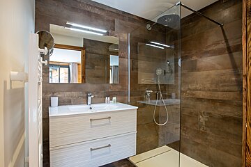 A bathroom with a walk in shower and a sink
