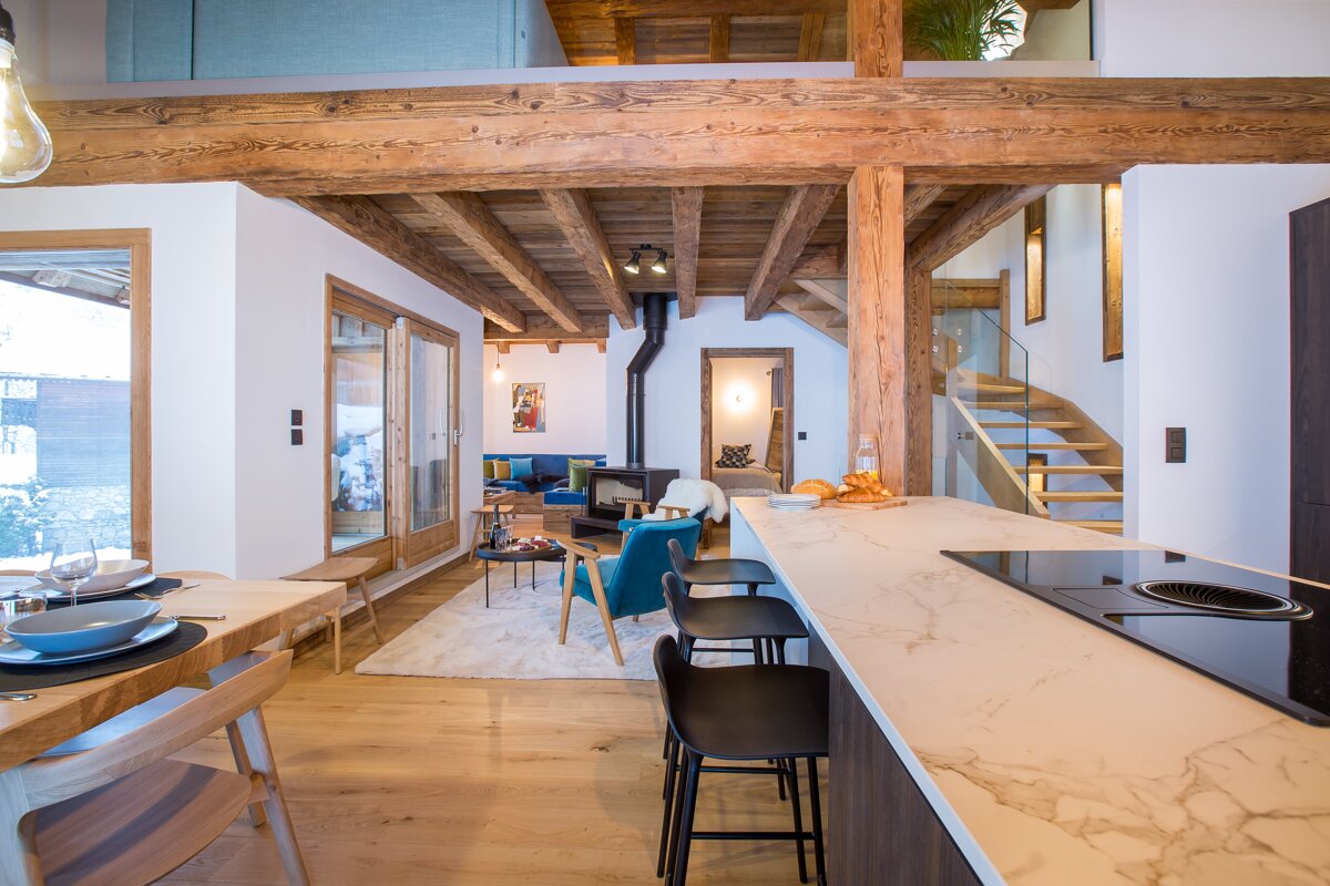 A kitchen with a marble counter top and wooden beams
