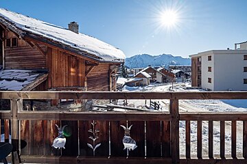 A balcony with a view of a snowy village and mountains