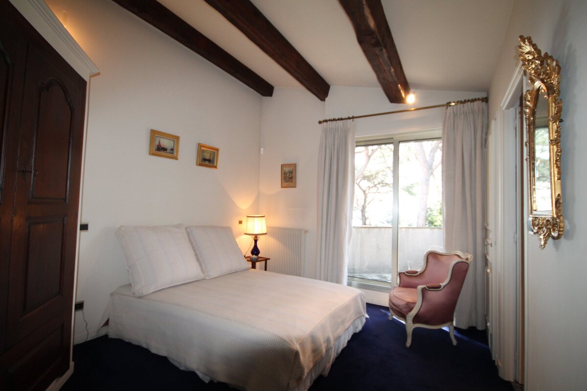 A bedroom with a bed a chair and a mirror