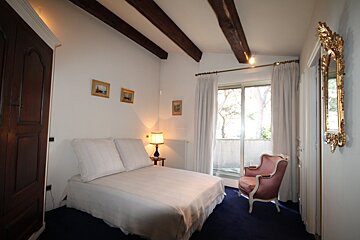 A bedroom with a bed a chair and a mirror