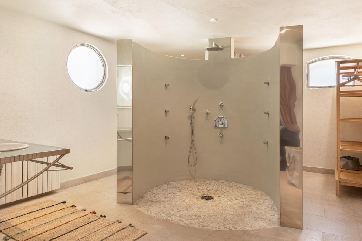 A bathroom with a round window and a walk in shower