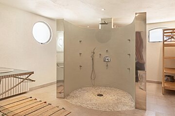 A bathroom with a round window and a walk in shower