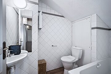 A bathroom with white tiles and a toilet