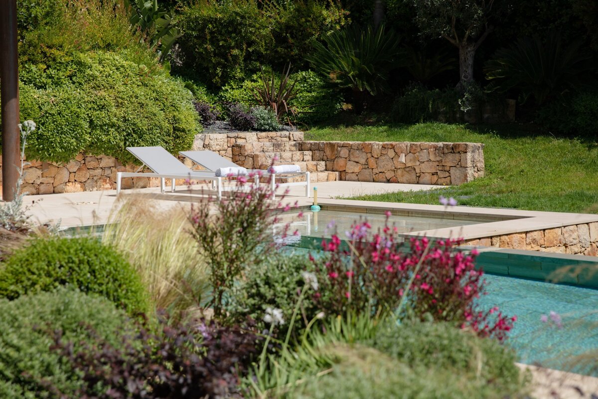 A swimming pool surrounded by flowers and a stone wall