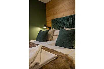 A bed with green pillows and a fur blanket