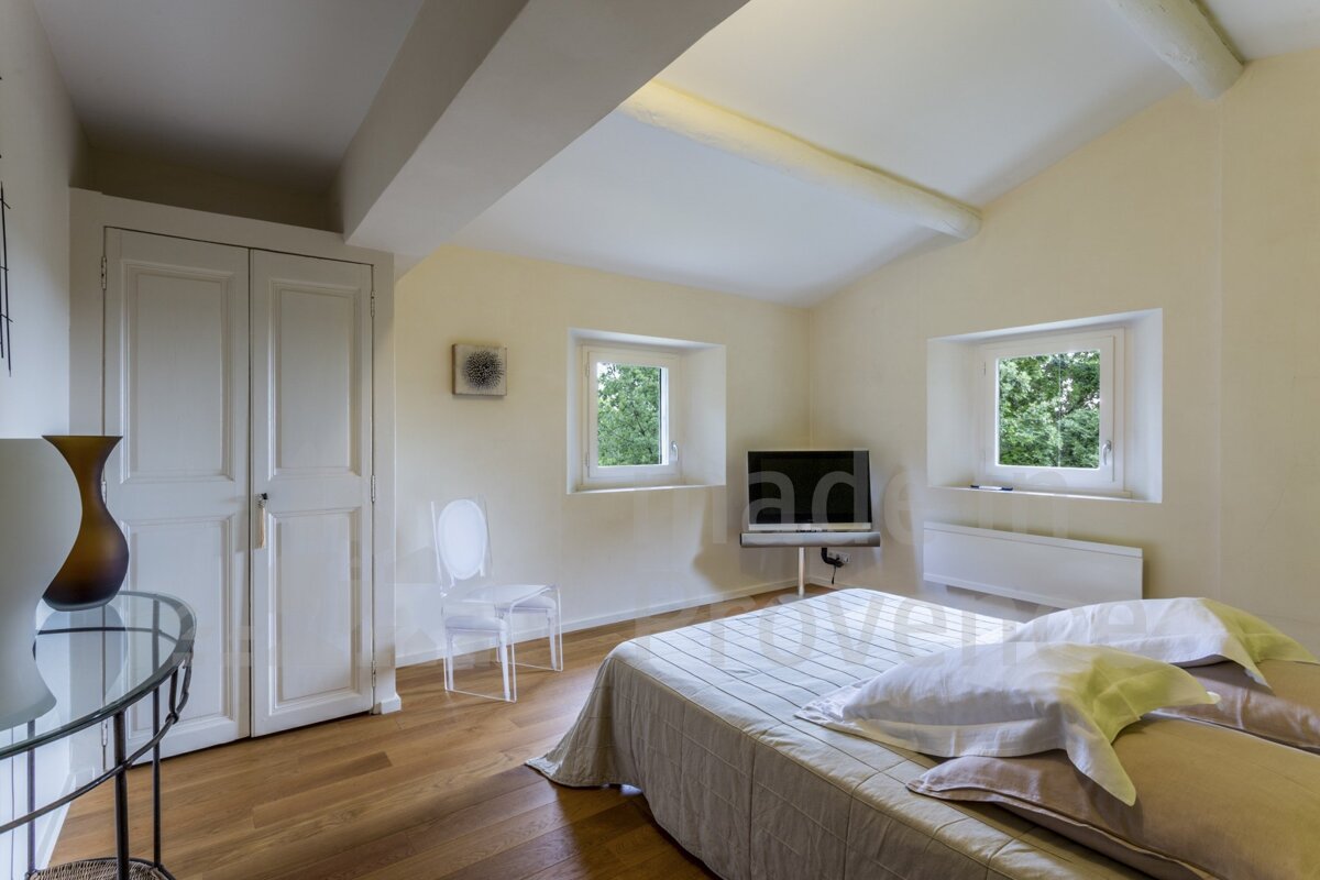 A bedroom with a bed a chair and a flat screen tv