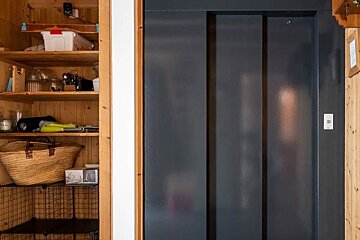 A black elevator is behind a wooden cabinet