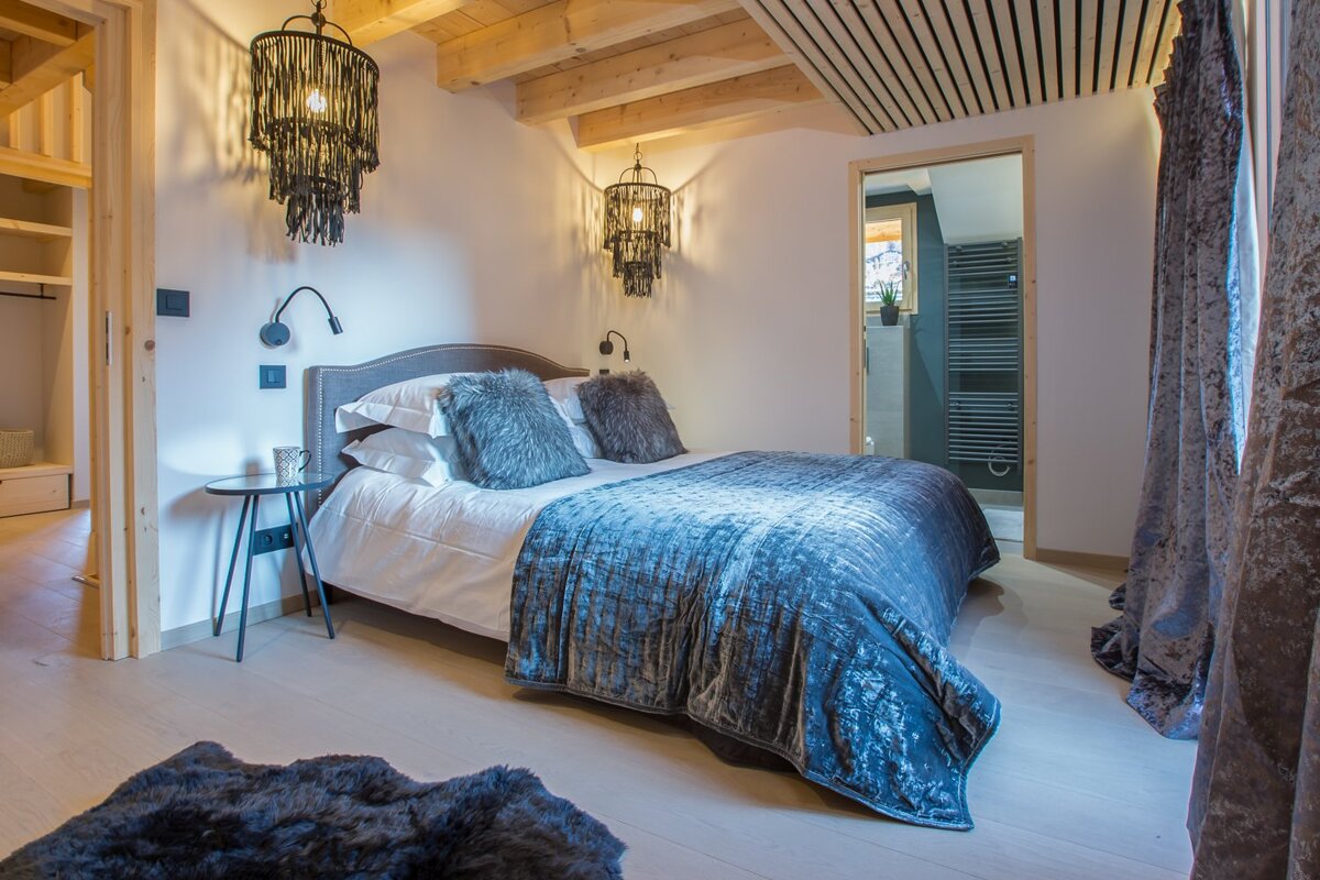 A bedroom with a bed and two lamps on the wall