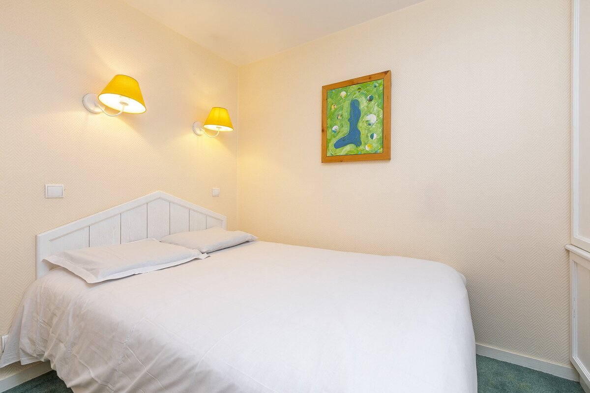 A bedroom with a picture of a golf course on the wall above the bed