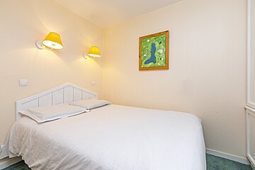 A bedroom with a picture of a golf course on the wall above the bed