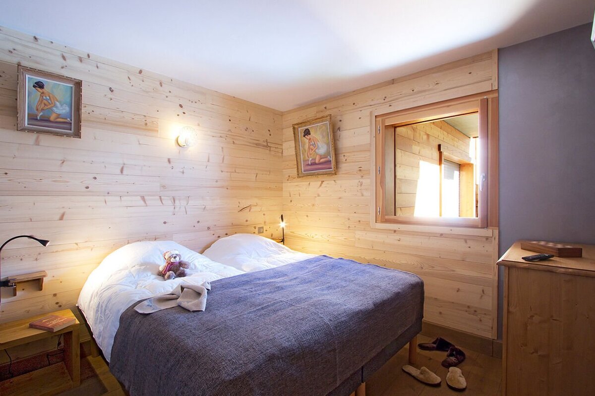 A bedroom with a bed and two paintings on the wall