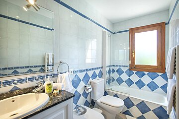 A bathroom with blue and white tiles and a sink and toilet