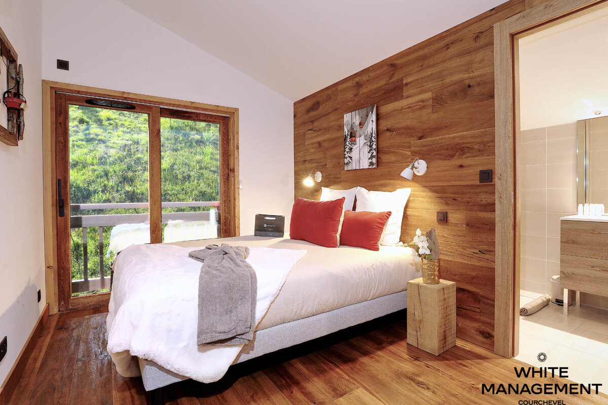 A bedroom with a bed and a rental designer logo