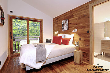 A bedroom with a bed and a rental designer logo