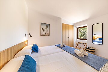 A bedroom with two beds and a picture of palm trees on the wall