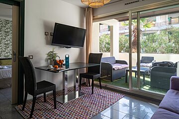 A living room with a table and chairs and a flat screen tv