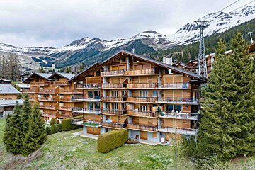 A building with a lot of balconies and mountains in the background