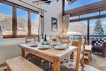 A dining room table with a bottle of wine on it
