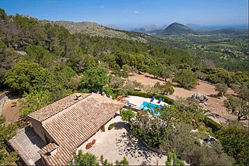 An aerial view of a house with a pool in the middle of a forest