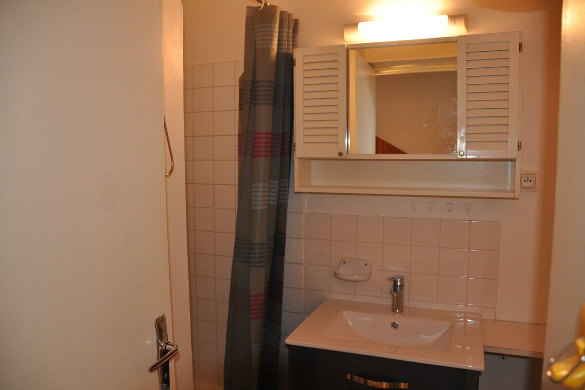 A bathroom with a sink a mirror and a shower curtain