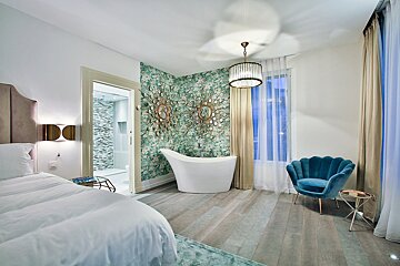 A bedroom with a bathtub and a blue chair