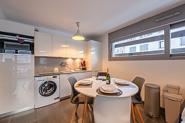 A kitchen with a table and chairs and a washing machine