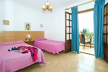 A bedroom with two pink beds and blue curtains