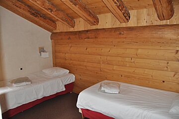 A bedroom with two beds and a wooden wall