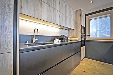 A kitchen with a sink and a window with trees in the background