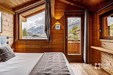 A bedroom with a mountain base real estate logo on the wall