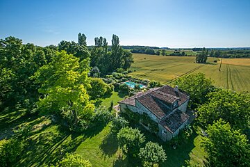 An aerial view of a house surrounded by trees and fields