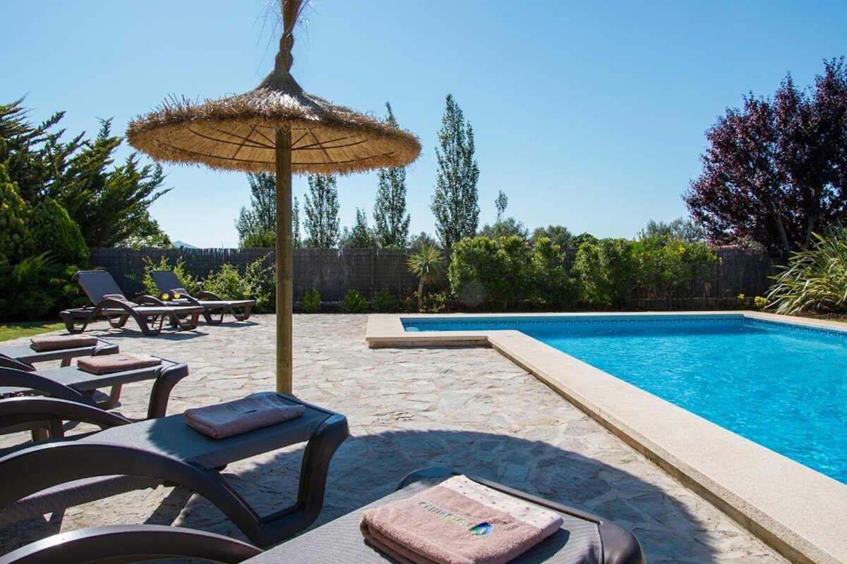 A swimming pool with a straw umbrella and chairs