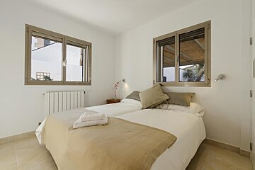 A bedroom with two beds and two windows