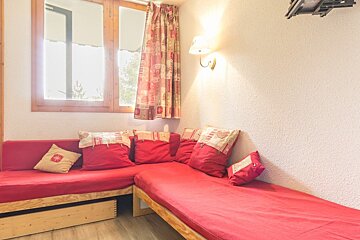 A living room with a red couch and red pillows