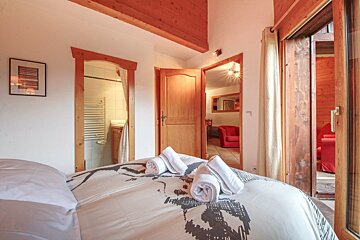 A bedroom with a skull blanket and towels on the bed