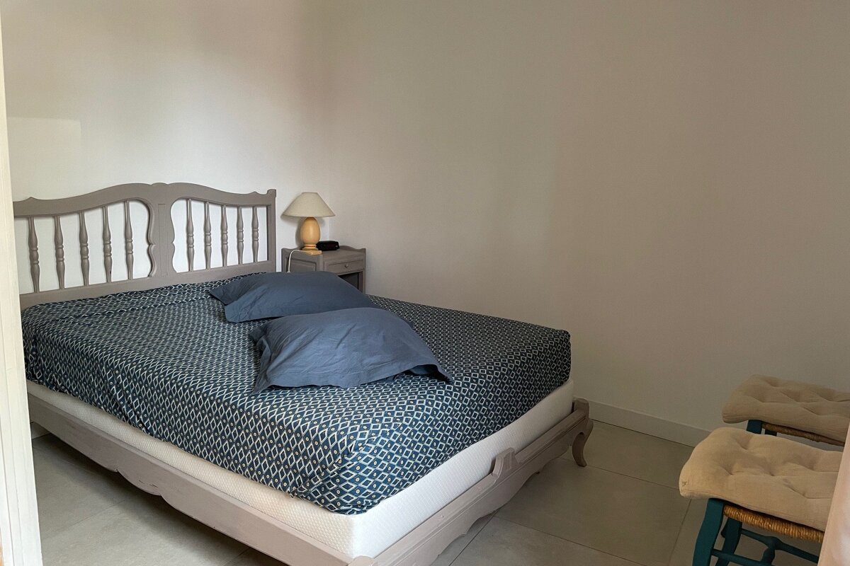 A bedroom with a bed a nightstand and a lamp