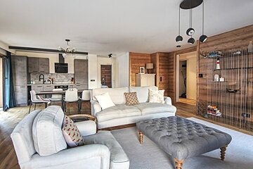 A living room with a white couch and a grey ottoman