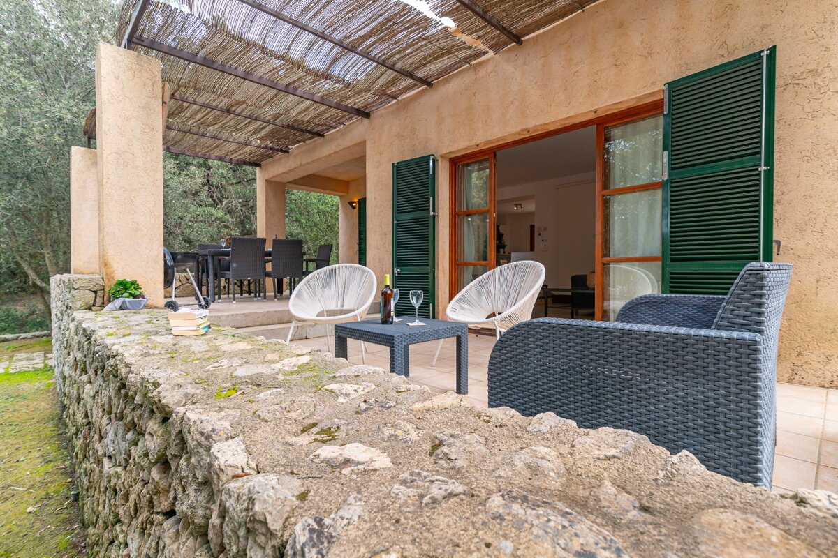 A patio with chairs and a table with a bottle of wine on it