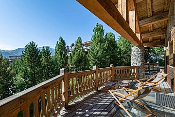 A wooden balcony with a view of trees and mountains